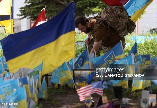 Ukrainian serviceman places national flags with the names of his fallen comrades at a makershift memorial for the fallen Ukrainian soldiers on...