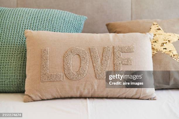 close-up of a cushion with the word love printed on it on a sofa with no people around. front view - cuscino foto e immagini stock