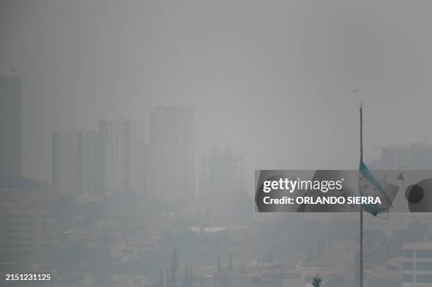 Honduran national flag flies amidst a dense layer of smoke covering Tegucigalpa on May 6, 2024. The Honduran capital faces pollution problems due to...