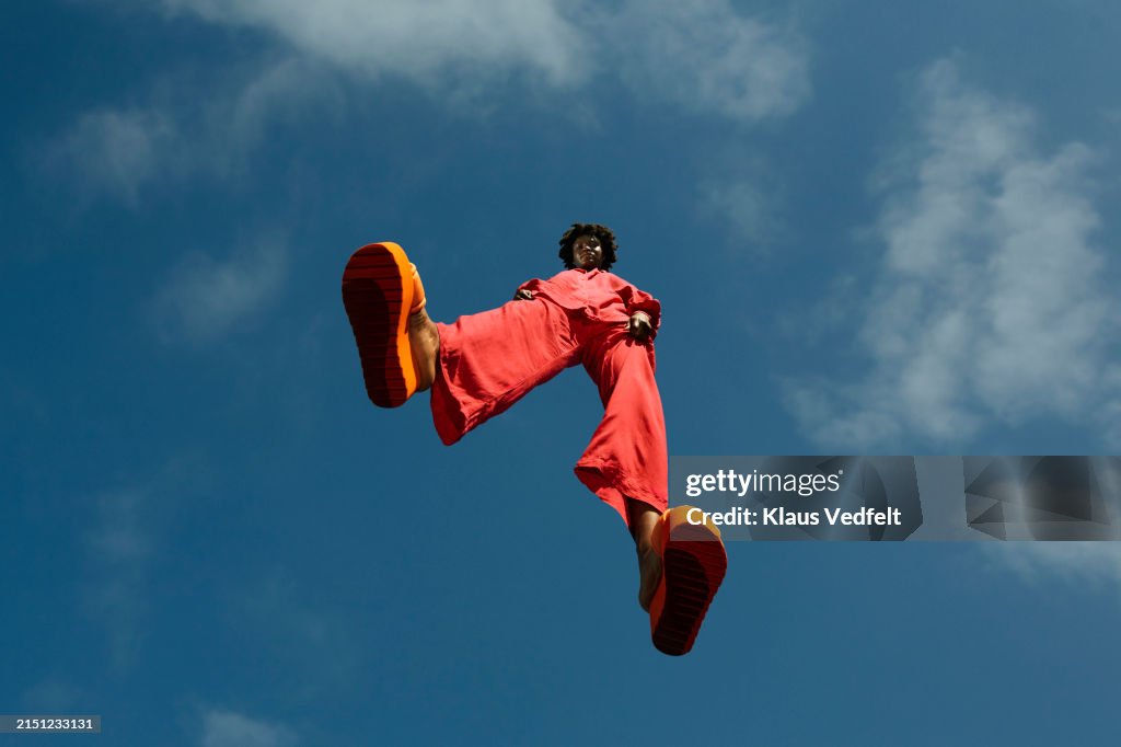 Confident young woman in red casuals levitating mid-air