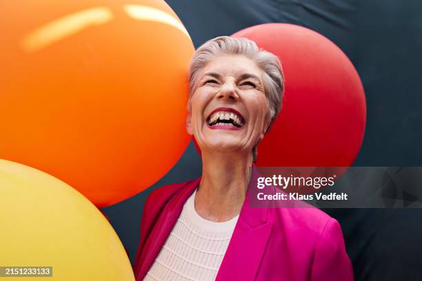 cheerful senior woman with balloons looking up - zwinkern stock-fotos und bilder