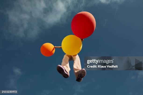 young woman with balloons flying high up - parte inferior fotografías e imágenes de stock
