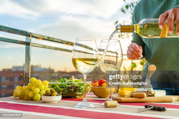 frau gießt weißwein auf terrassentisch - weißwein stock-fotos und bilder