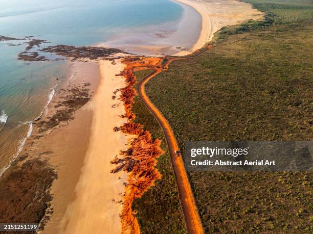 aerial image showing a 4x4 driving on a dirt road next to the sandstone cliffs at james price point, broome, the kimberley, western australia, australia - the kimberley stock pictures, royalty-free photos & images