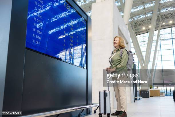 travel time - senior woman looking at the departure board - digital signage stock pictures, royalty-free photos & images