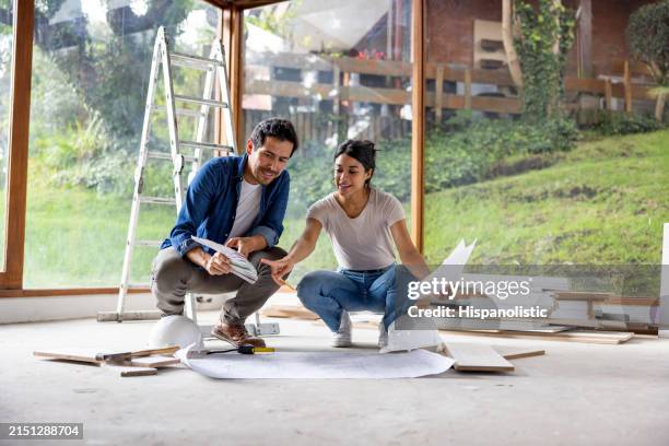 pareja compartiendo algunas ideas de decoración mientras renuevan su casa - renovación del hogar fotografías e imágenes de stock