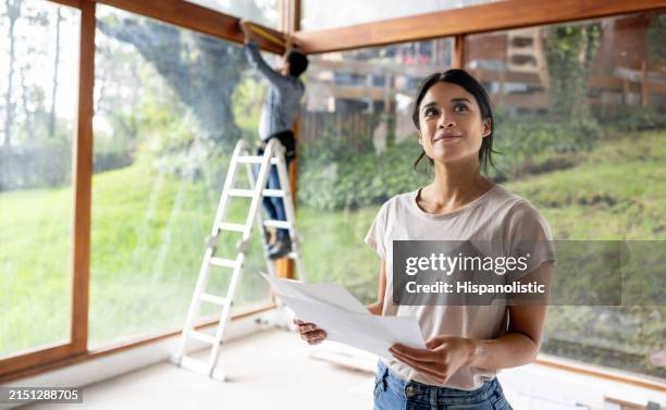 architect renovating a house and holding designs at the construction site - ampliação da casa imagens e fotografias de stock