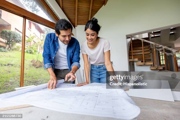 couple regardant les plans tout en rénovant leur maison - rénovation intérieure photos et images de collection
