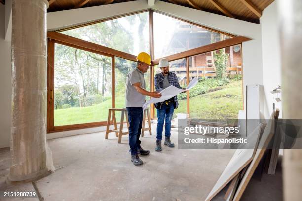 architecte et ouvrier du bâtiment regardant un plan lors de la rénovation d’une maison - entrepreneur en bâtiment photos et images de collection