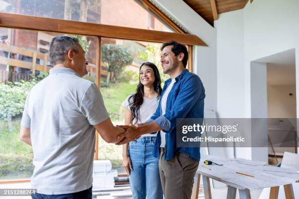 couple greeting the architect remodeling their house - byggnadsentreprenör bildbanksfoton och bilder