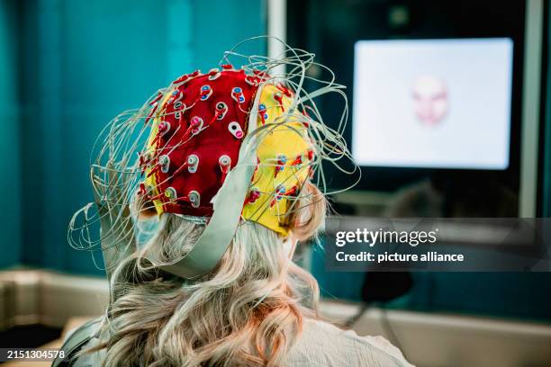 April 2024, Thuringia, Jena: A test subject wears an EEG cap with electrodes for the EEG measurement while completing the test tasks in an isolated...