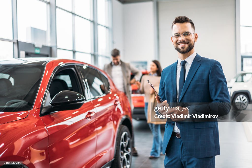 Car salesman with clipboard in showroom
