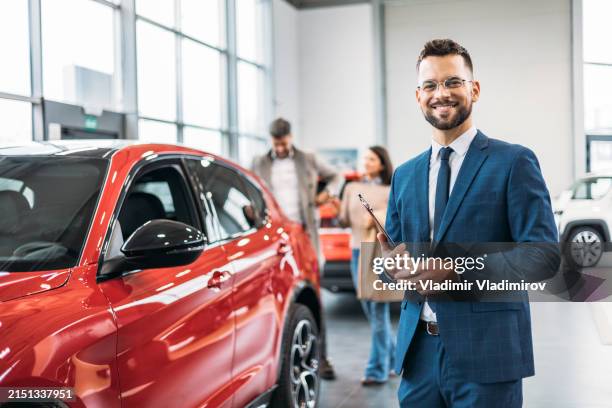 car salesman with clipboard in showroom - autoverkoper stockfoto's en -beelden