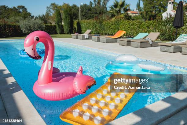 various pool floats floating in an empty pool - plastic garden chair fotografías e imágenes de stock