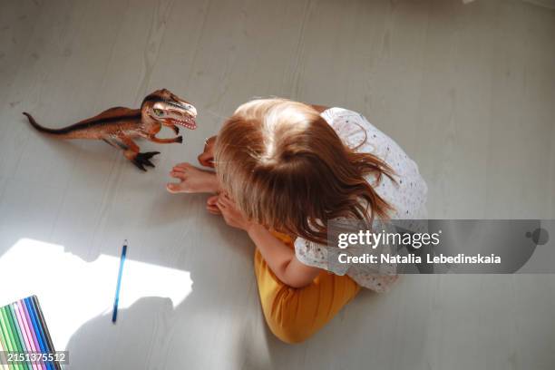 joyful kid engaging with dinosaur toy and its shadow while sitting on floor at home, early learning and playtime, top view - plastic animals stock pictures, royalty-free photos & images