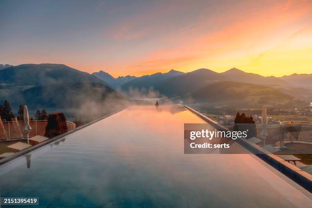 young woman relaxing in the infinity pool with a nature landscape view in dolomites, italy - infinity pool stock-fotos und bilder