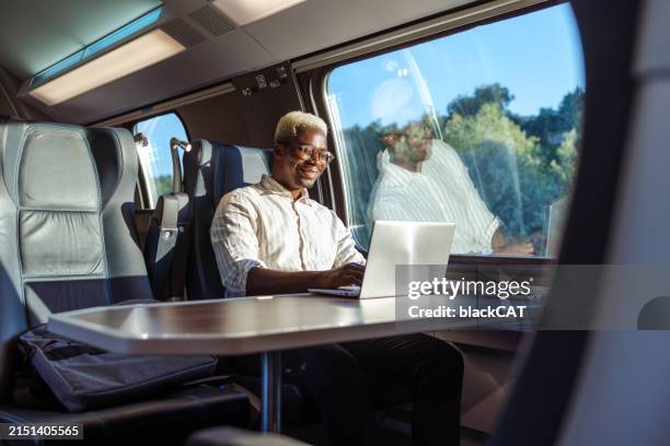 african american businessman working on laptop at the train - tåg bildbanksfoton och bilder