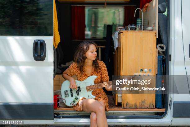 woman playing electric guitar in camper van - amplifier stock pictures, royalty-free photos & images