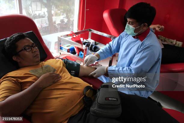 Medical worker is drawing blood while volunteers are donating blood in Medan, Indonesia, to commemorate World Red Cross and Crescent Day.