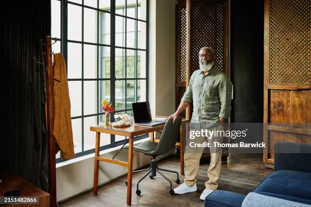 wide shot portrait smiling senior man standing at desk in hotel suite - black man full body portrait stock pictures, royalty-free photos & images
