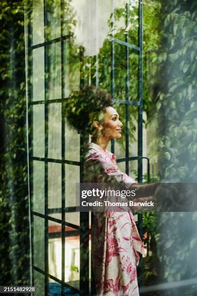 medium wide shot woman in doorway to rooftop garden of hotel suite - hotel suite stock pictures, royalty-free photos & images