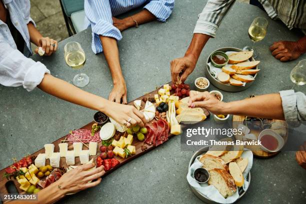 medium shot hands reaching for appetizers on platter during party - snijplank stockfoto's en -beelden