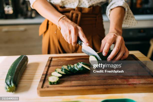 woman slicing fresh zucchini on a wooden cutting board - knife cut hand stock pictures, royalty-free photos & images