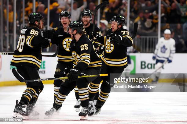 David Pastrnak of the Boston Bruins celebrates with Brandon Carlo, Charlie McAvoy and John Beecher after scoring the game winning goal against the...