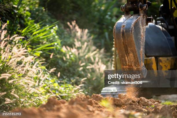 excavator at work on farm site: soil digging for agricultural development and land preparation - digger wheel stock pictures, royalty-free photos & images
