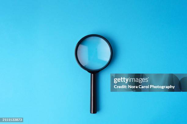 magnifying glass on blue background - magnifying glass stock pictures, royalty-free photos & images