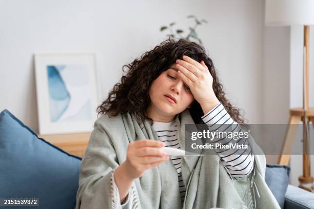unwell woman checking temperature at home - feber bildbanksfoton och bilder