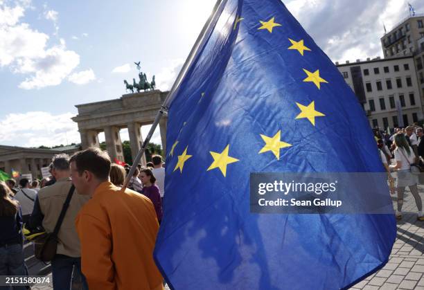 People, including one participant with a flag of the European Union, gather in front of the Brandenburg Gate to protest against recent beatings of...