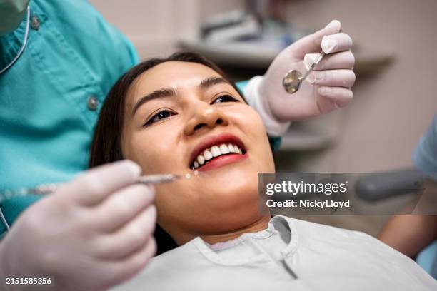 lächelnde patientin, die sich einer zahnärztlichen behandlung unterzieht - zahnkaries stock-fotos und bilder