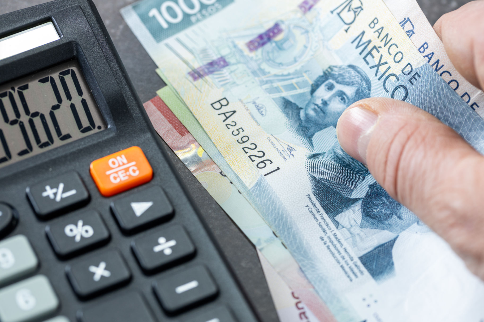 Mexican pesos banknotes, Calculator and money file, financial settlements, household budget, taxes, Mexico currency exchange rate, financial analysis, economic and business concept Mexican pesos banknotes, Calculator and money file, financial settlements, household budget, taxes, Mexico currency exchange rate, financial analysis, economic and business concept