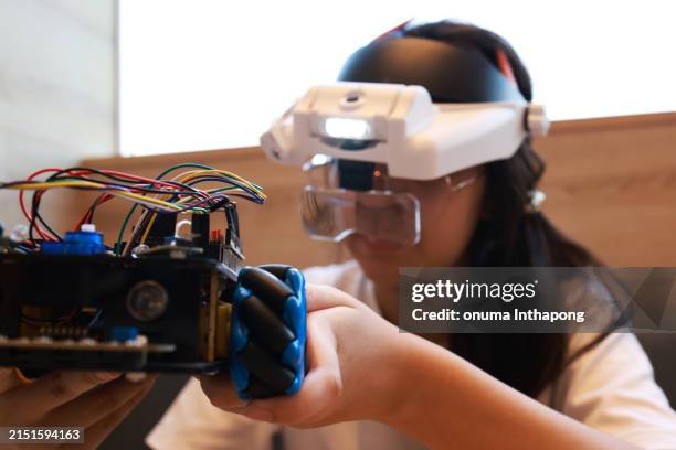 a cute girl wearing a virtual reality glasses (vr) headset and moving her hands around to work on her virtual robot assembly.robotics and self-learning at home - virtual reality point of view stock pictures, royalty-free photos & images