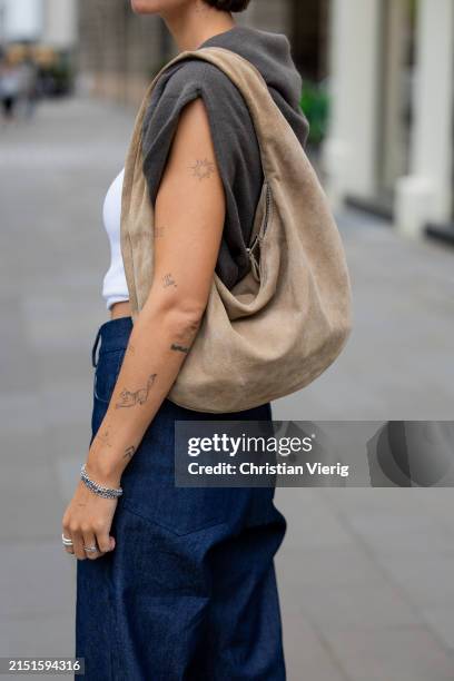 Jacqueline Zelwis wears navy blue ONWEEKENDS jeans, white sleeveless Sezane top, Samsoe Samsoe pullover, light brown Flattered bag on May 05, 2024 in...