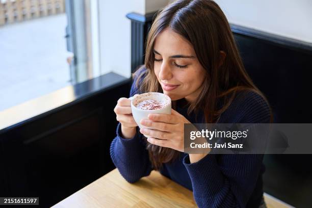mujer disfrutando del aroma del cappuccino fresco en un café - chica-tomando-cafe fotografías e imágenes de stock
