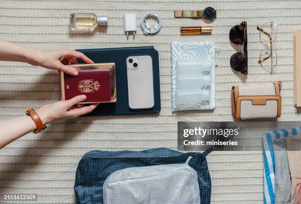foto de primer plano de las manos de una mujer sosteniendo un pasaporte mientras empaca una maleta en casa - cargador de móvil fotografías e imágenes de stock