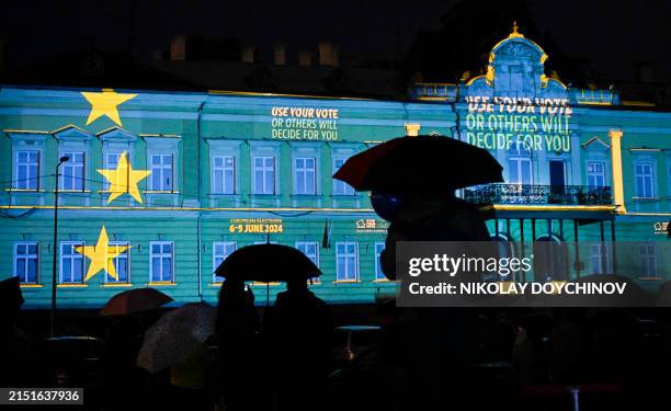 People watch how lightings are projected on the National Gallery of Art announcing the upcoming European Parliament elections, as part of the...