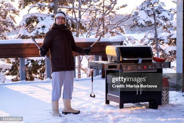a man cooks on a grill on the veranda of a large house in winter. - bbq winter ストックフォトと画像