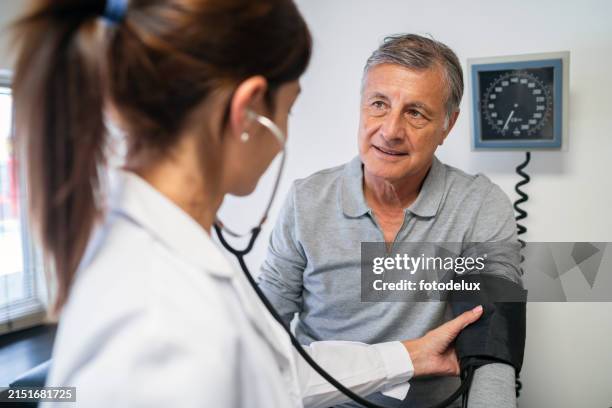 senior man getting blood pressure checked by doctor - blood pressure gauge stock pictures, royalty-free photos & images