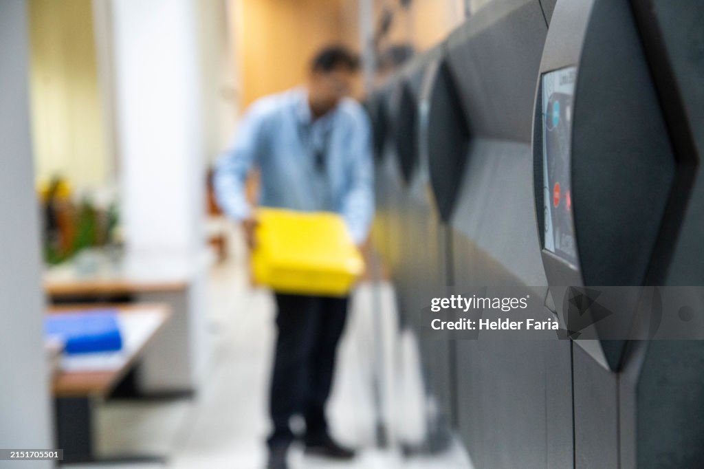 Automatic Mobile Compactor Filing Archive Storage Cabinets System. In the background blurred image of a man handling a yellow plastic file box