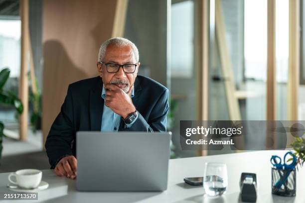 diversi dirigenti senior riflettono sulla strategia aziendale in ufficio - usare il computer foto e immagini stock