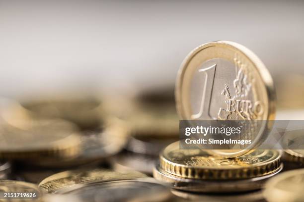one euro coin vertical placed on a pile of euro coins. euro money concept. - euros imagens e fotografias de stock