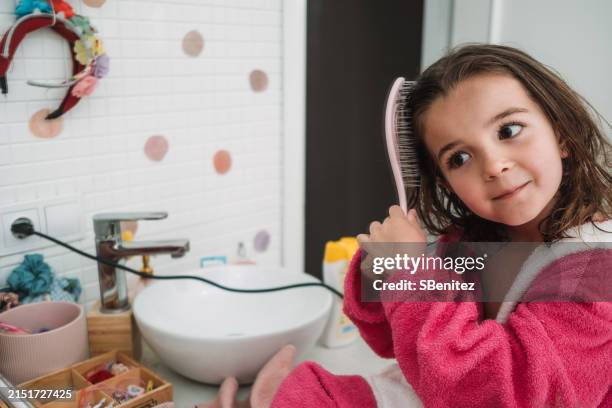 portrait of a girl combing her hair with a hairbrush after bathing - peinado fotografías e imágenes de stock