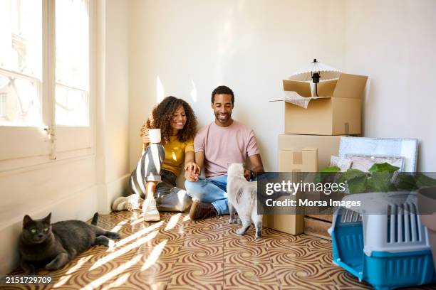 happy couple sitting with coffee cups in new home - moving house stock pictures, royalty-free photos & images