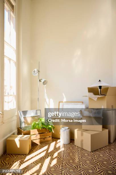 cardboard boxes with lamp by window in apartment - cardboard stock pictures, royalty-free photos & images
