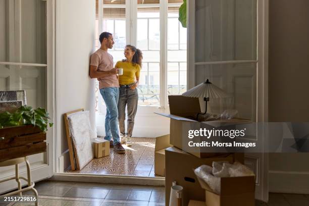 smiling man and woman talking in balcony at home - proprietario di casa foto e immagini stock
