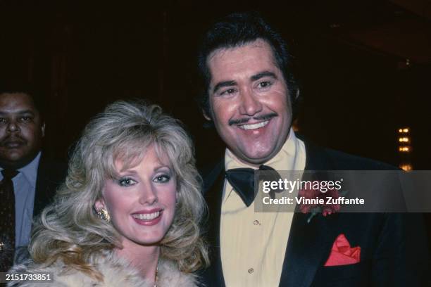 American actress Morgan Fairchild, wearing a fur coat and gold earrings, and American singer and actor Wayne Newton, who wears a tuxedo and bow tie,...