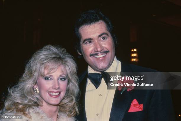 American actress Morgan Fairchild, wearing a fur coat and gold earrings, and American singer and actor Wayne Newton, who wears a tuxedo and bow tie,...